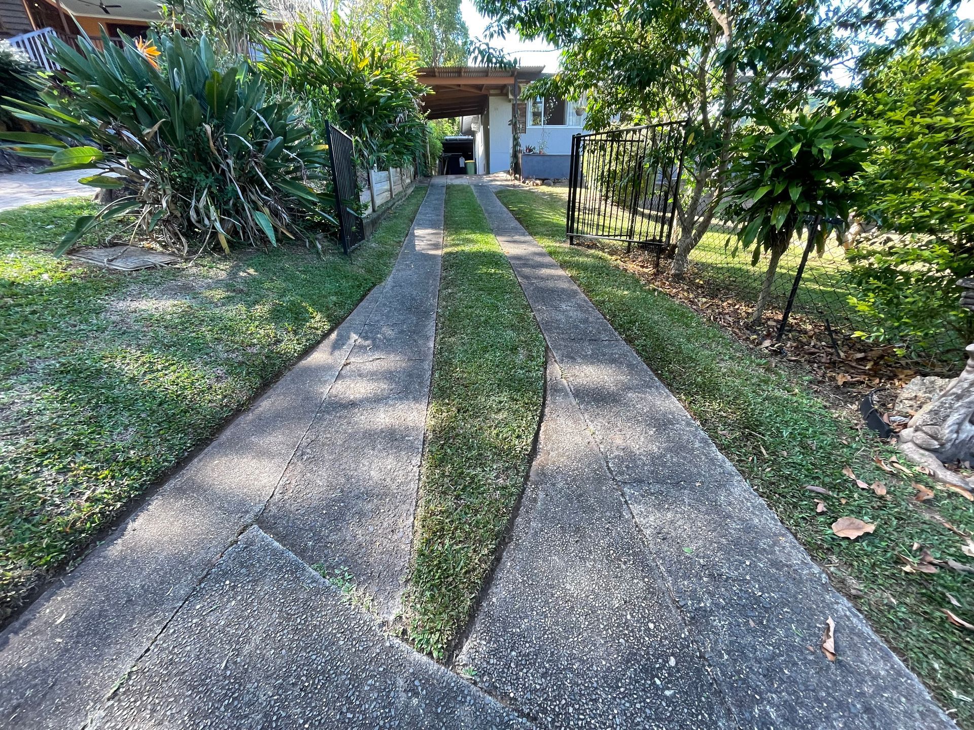 Concrete Driveway with Grassy Median Leads to A House with A Carport, and Trees — Lads Lawns & Gardens in Bentley Park, QLD