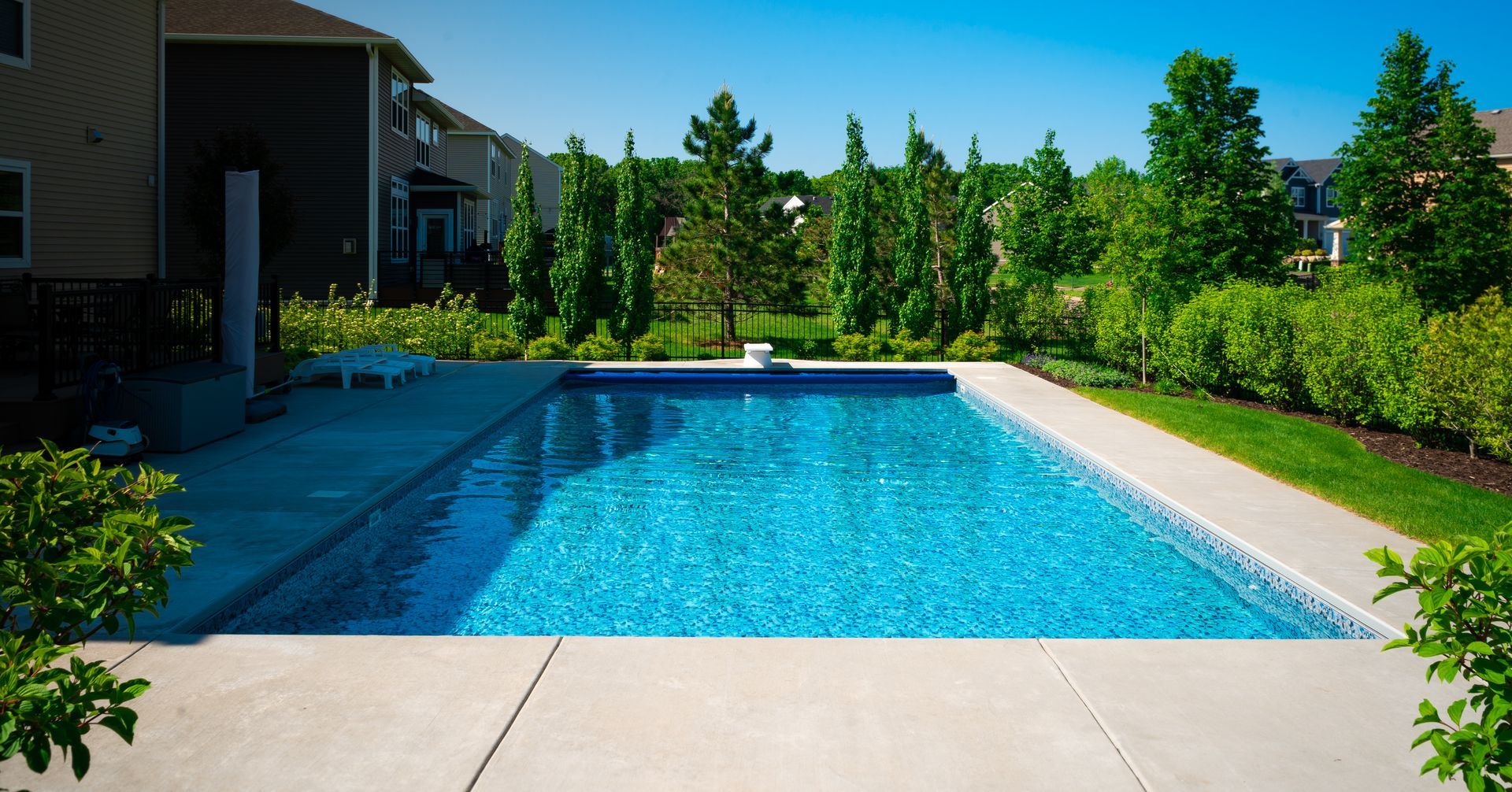 There is a large swimming pool in the backyard of a house.
