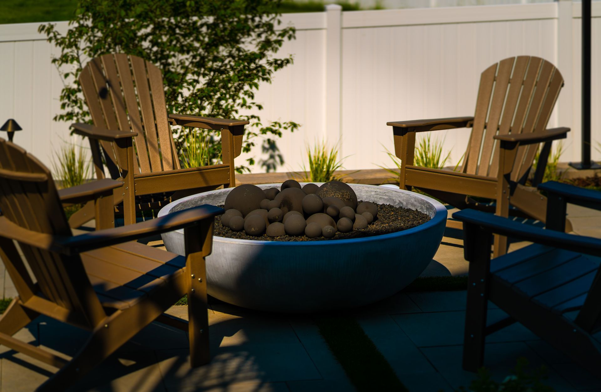 A fire pit surrounded by wooden chairs on a patio.