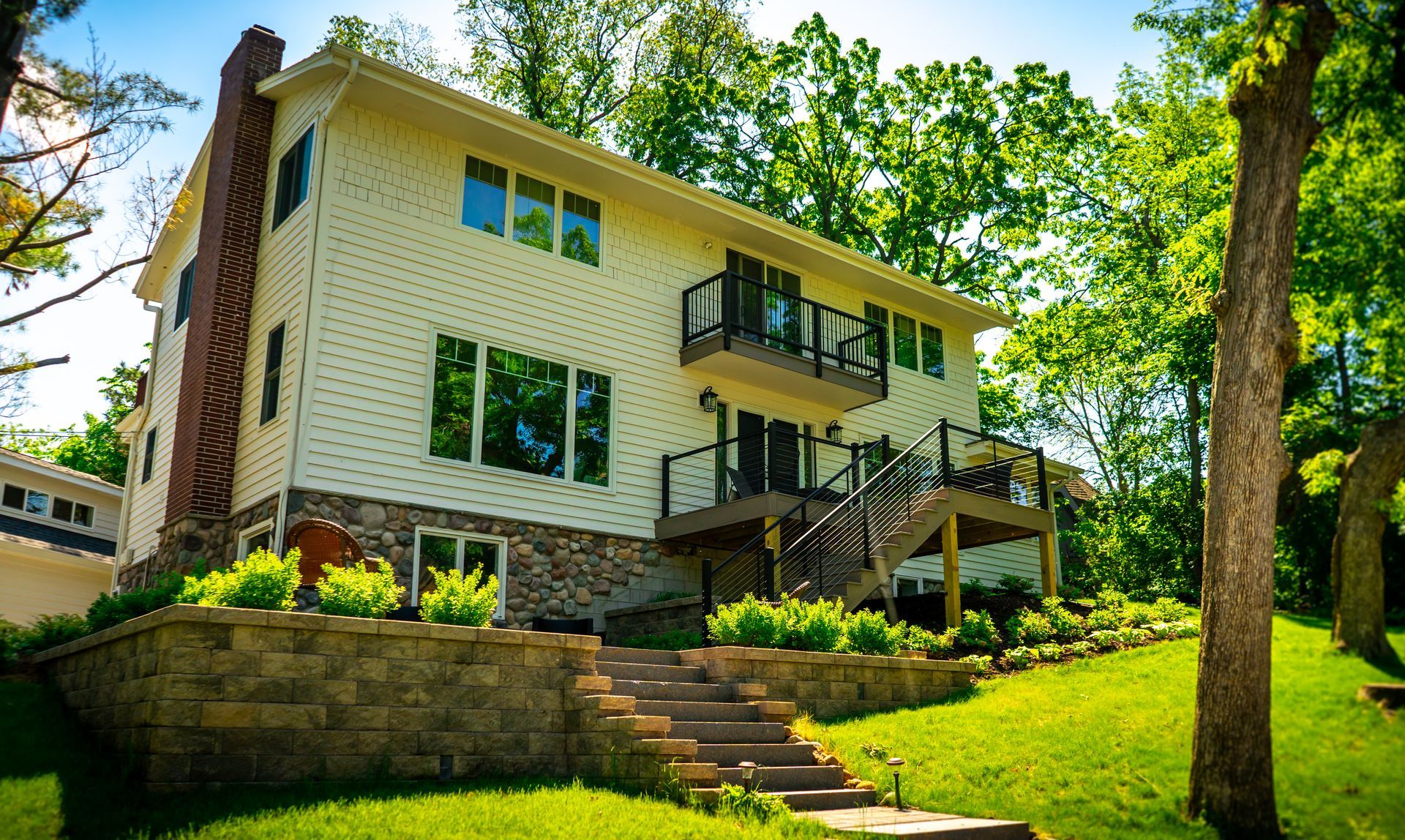A large house is sitting on top of a lush green hill surrounded by trees.