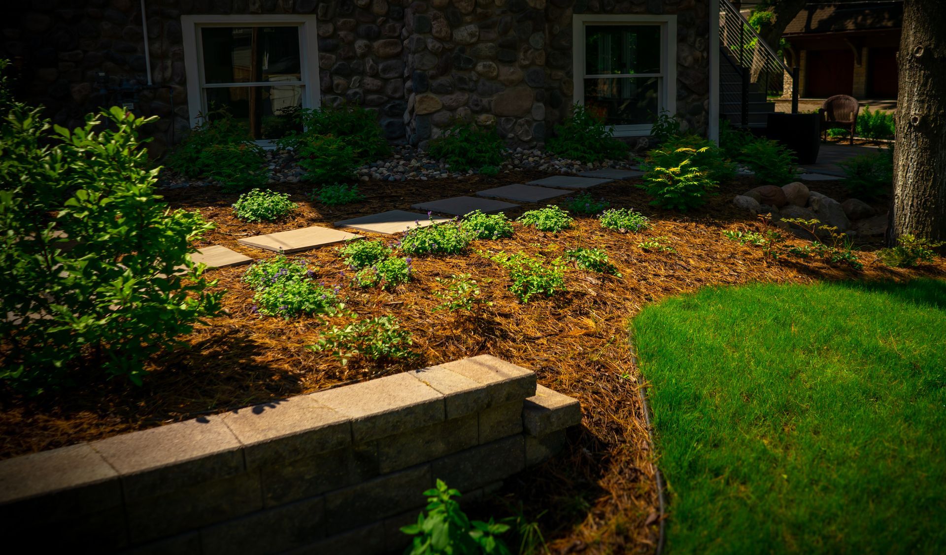 A stone house with a lush green lawn in front of it.