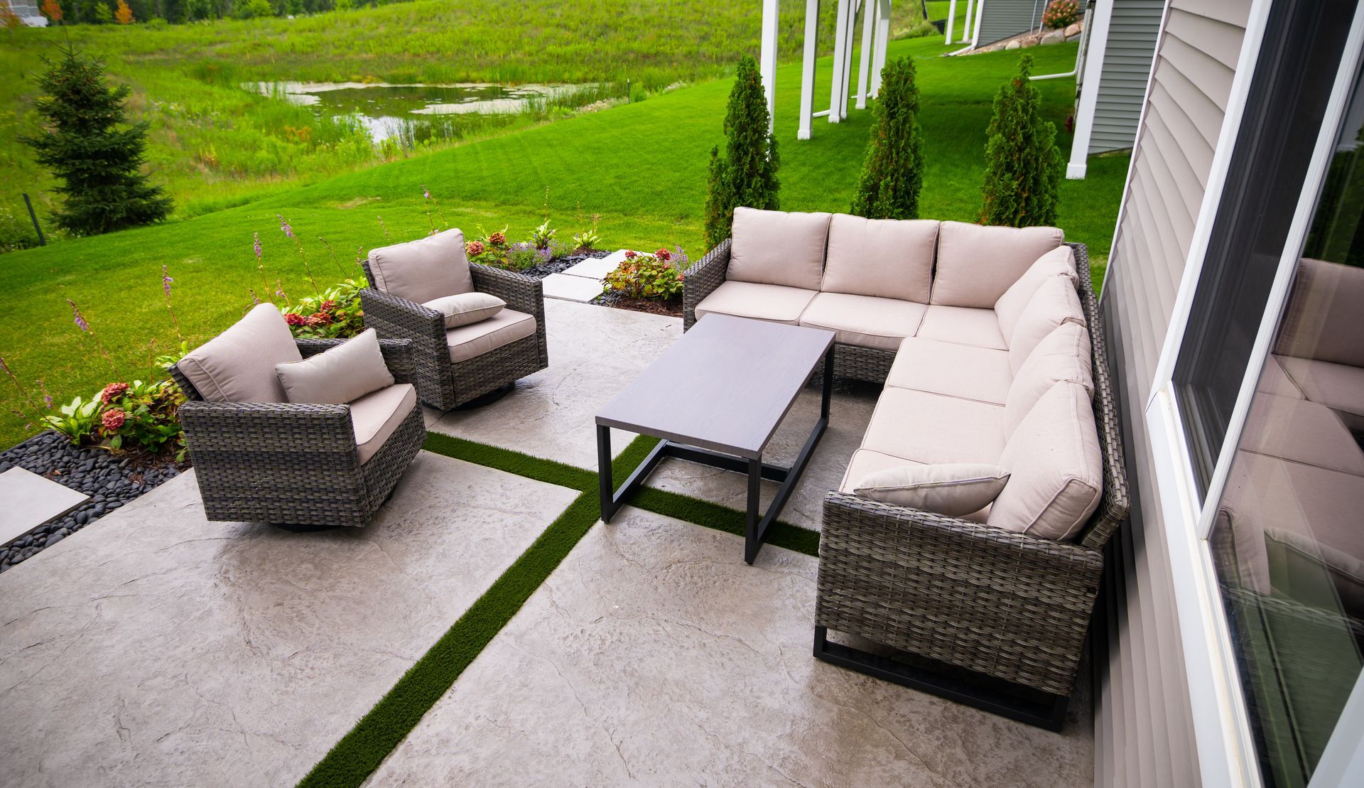 A patio with a sectional couch , chairs , and a table.