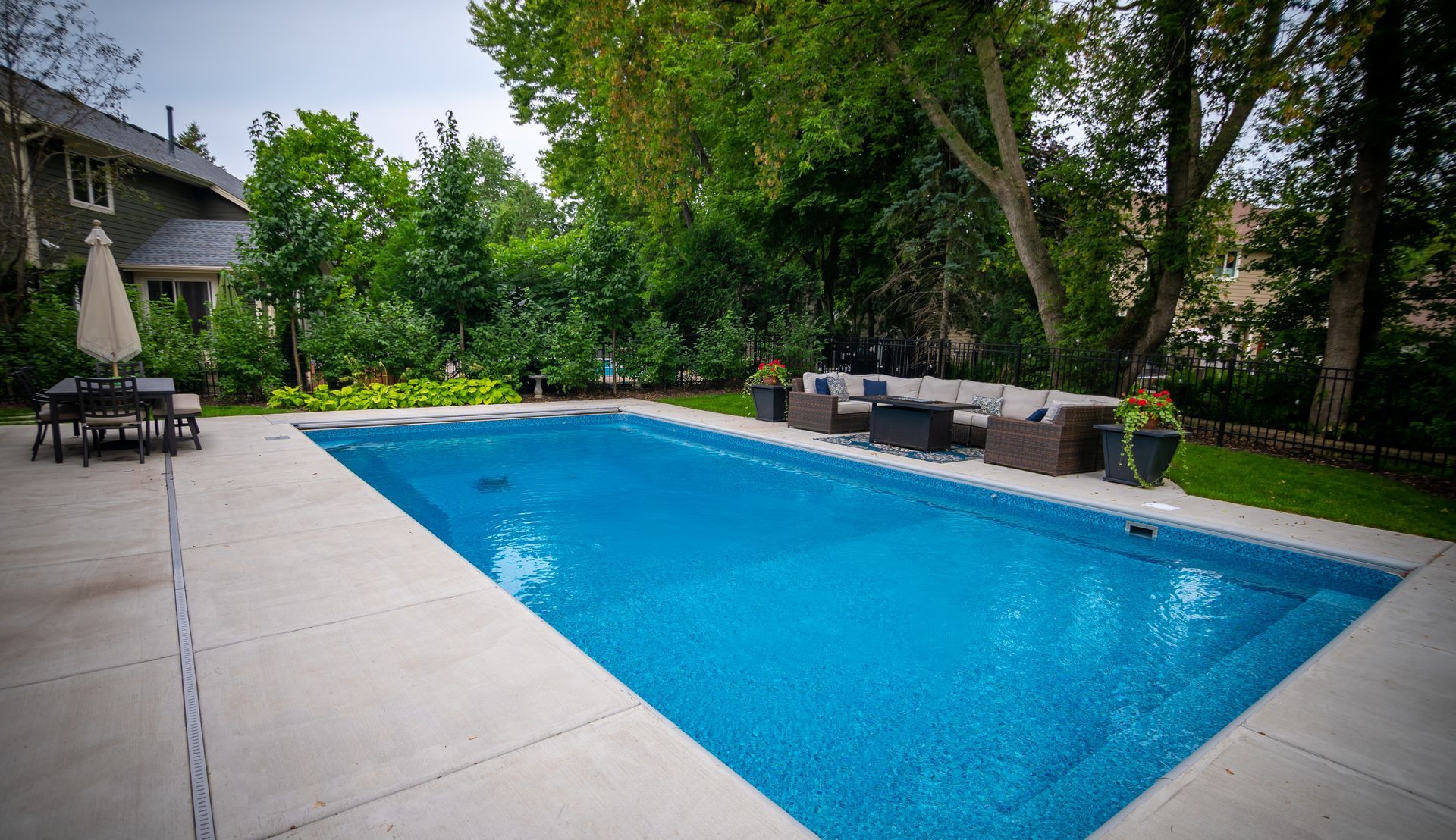There is a large swimming pool in the backyard of a house.