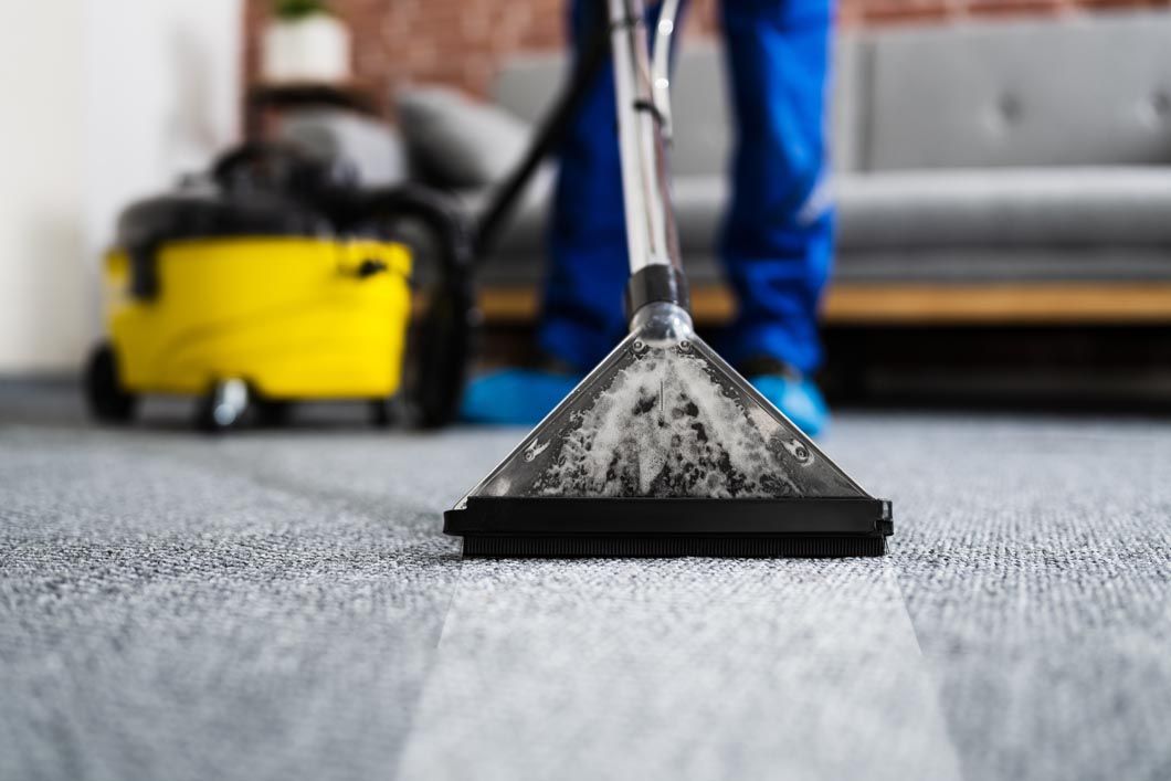 A person is cleaning a carpet with a vacuum cleaner.