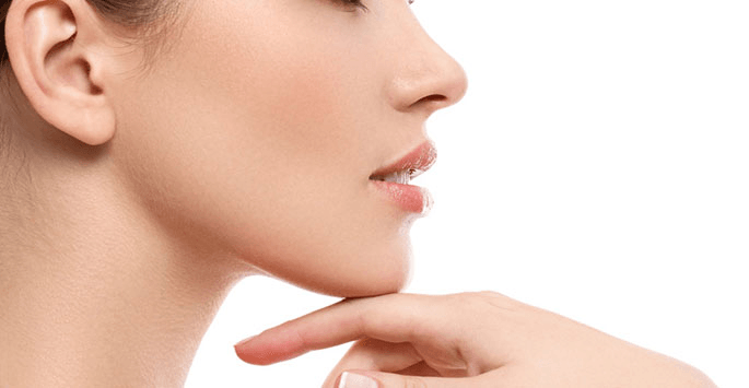 A close up of a woman 's face with her hand on her chin.