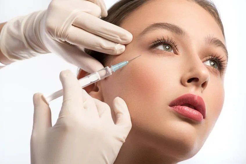 A woman is getting a botox injection in her eye.