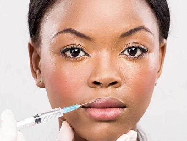 A woman is getting a botox injection in her lips.