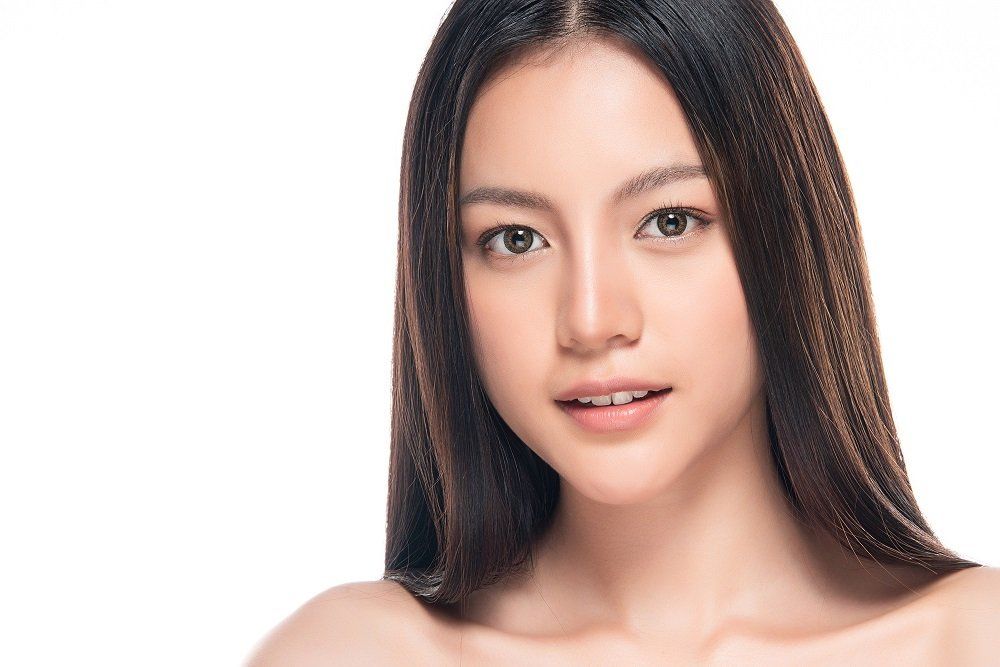 A close up of a woman 's face with long hair on a white background.