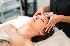 A woman is getting a head massage at a spa.