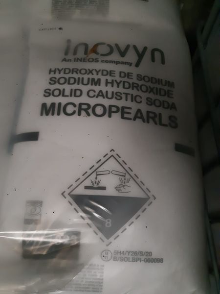 Busta di microperle di idrossido di sodio, con simbolo di pericolo corrosivo.