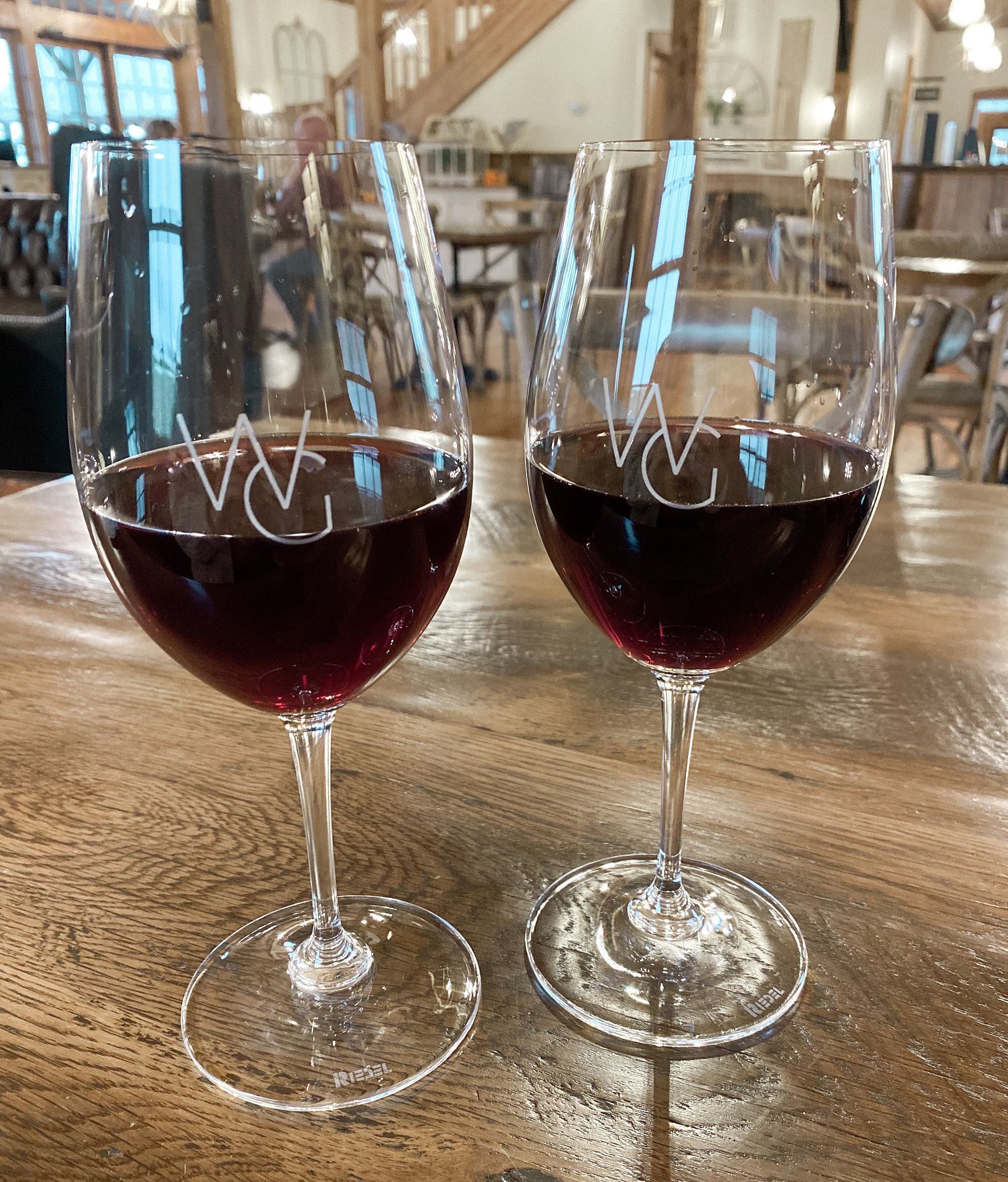 Two glasses of red wine are sitting on a wooden table.