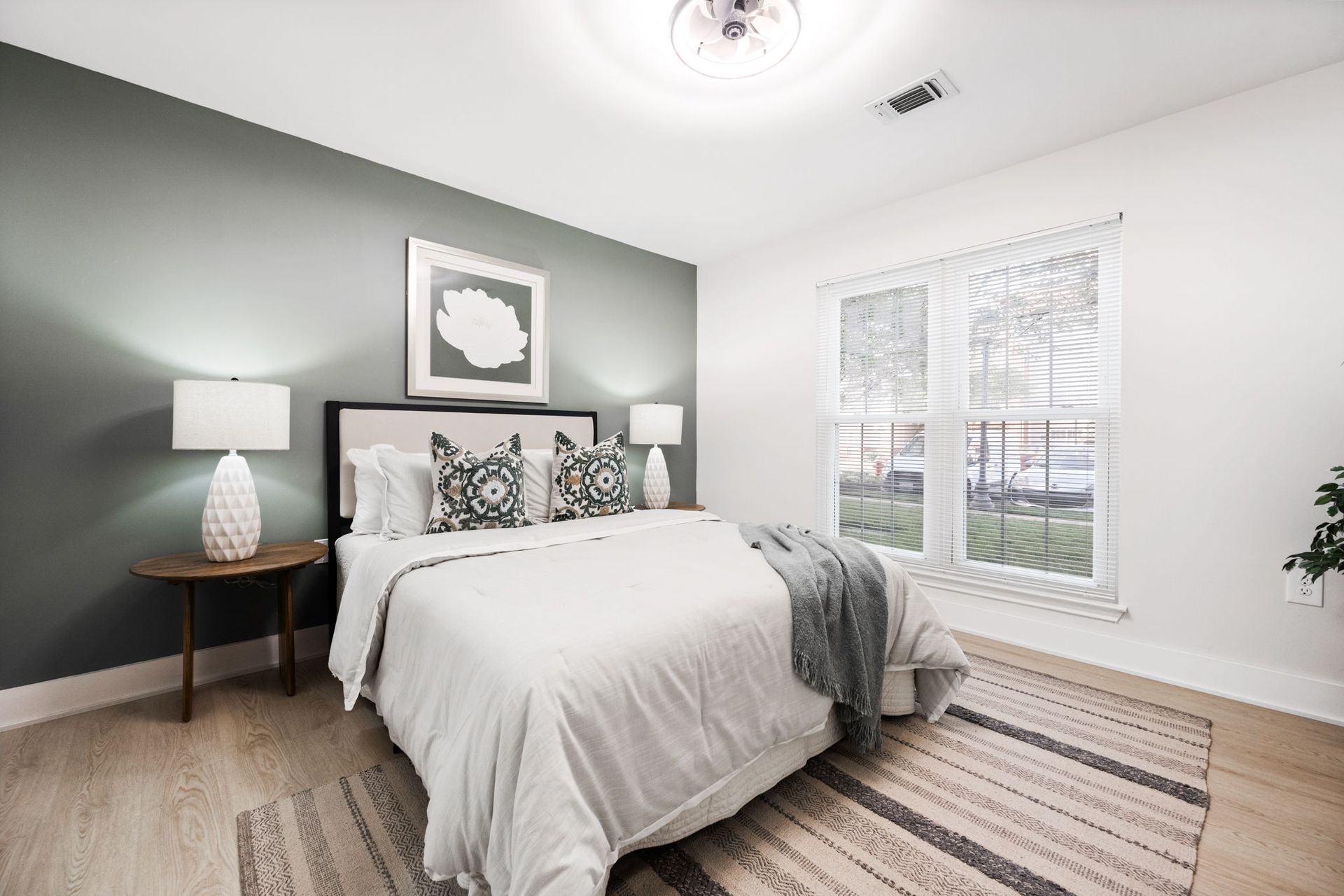 A bedroom with a bed , lamps , and a rug.
