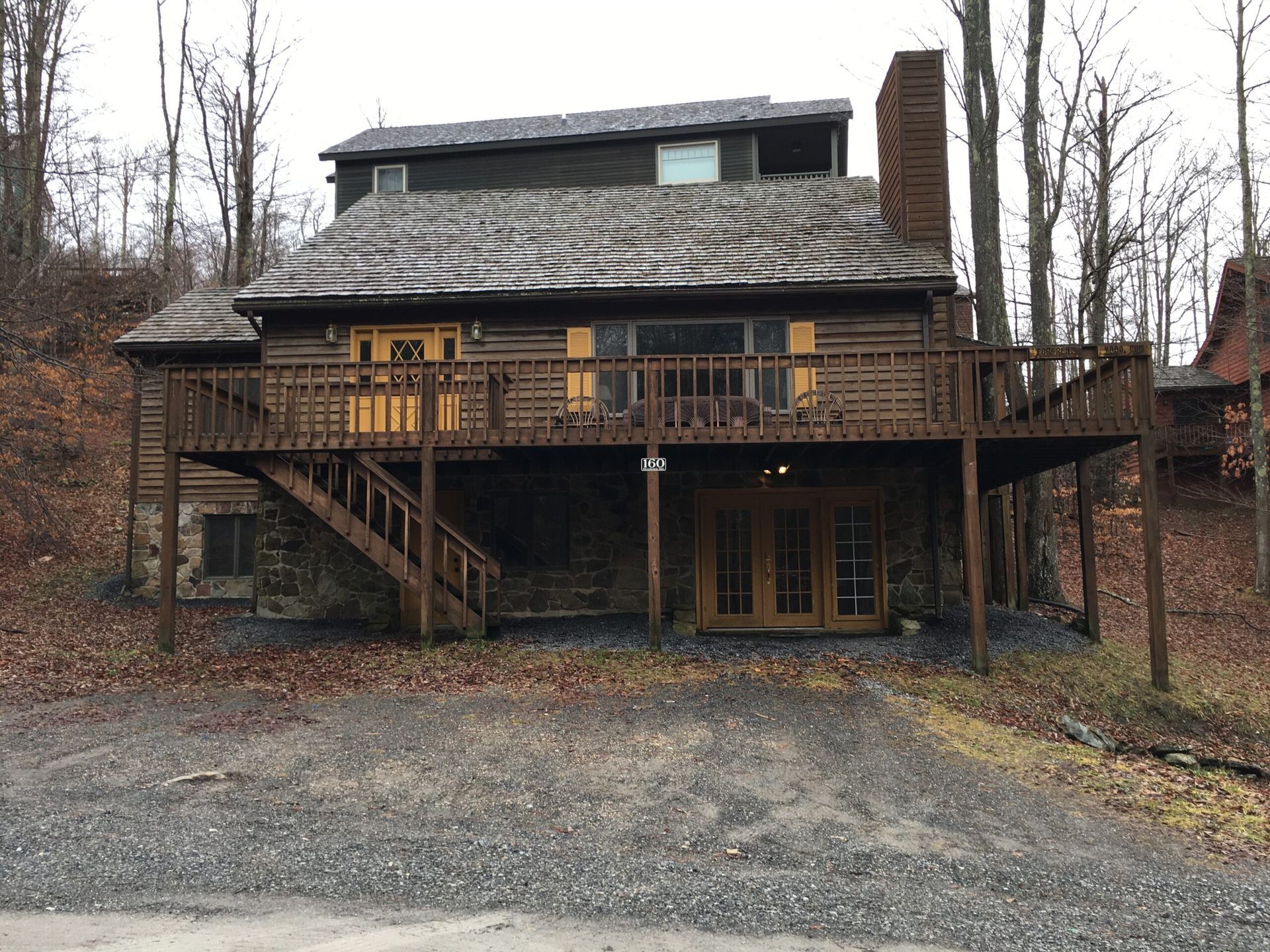 A large log cabin with a large deck and stairs