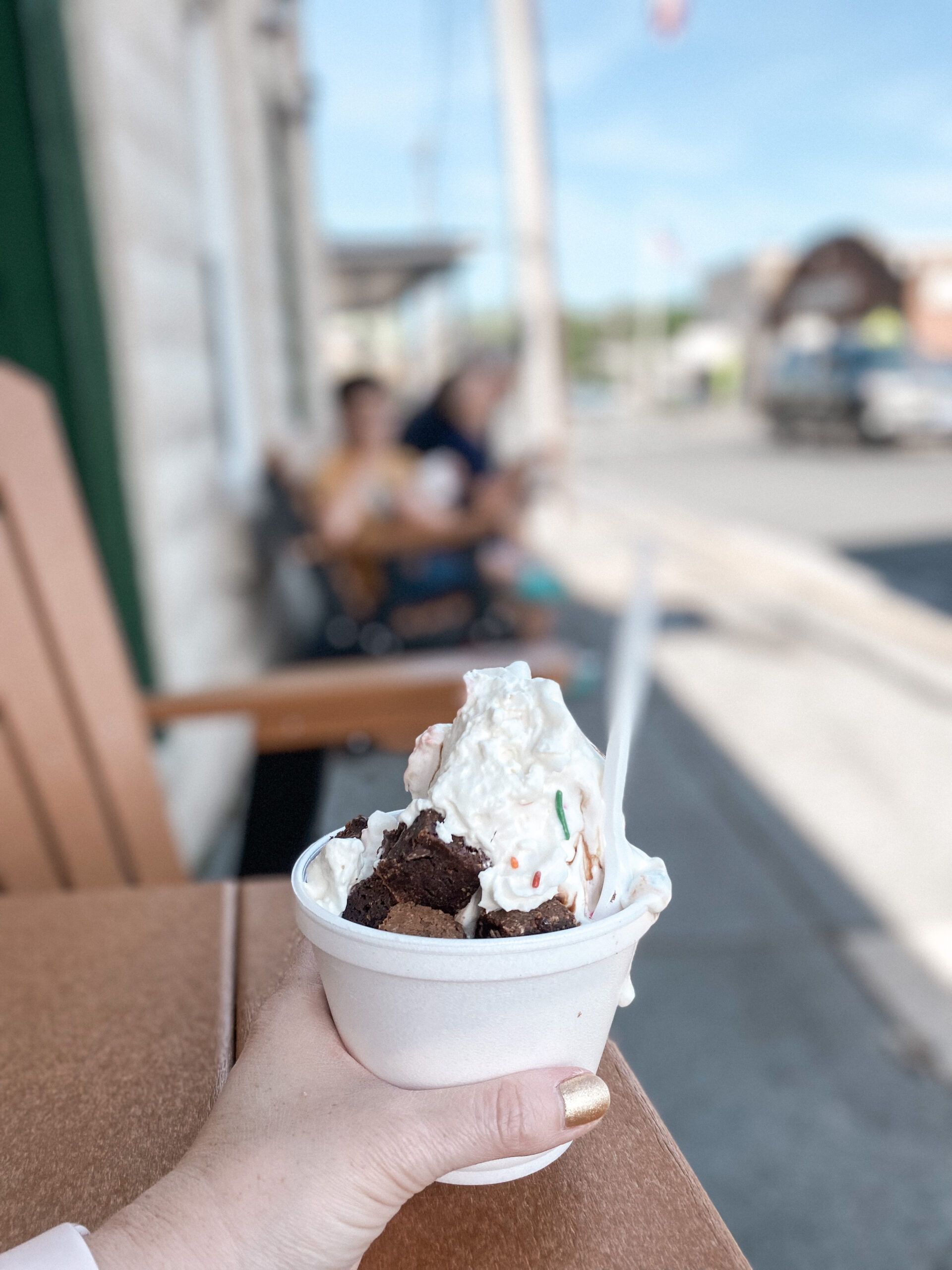 A person is holding a cup of ice cream on a table.