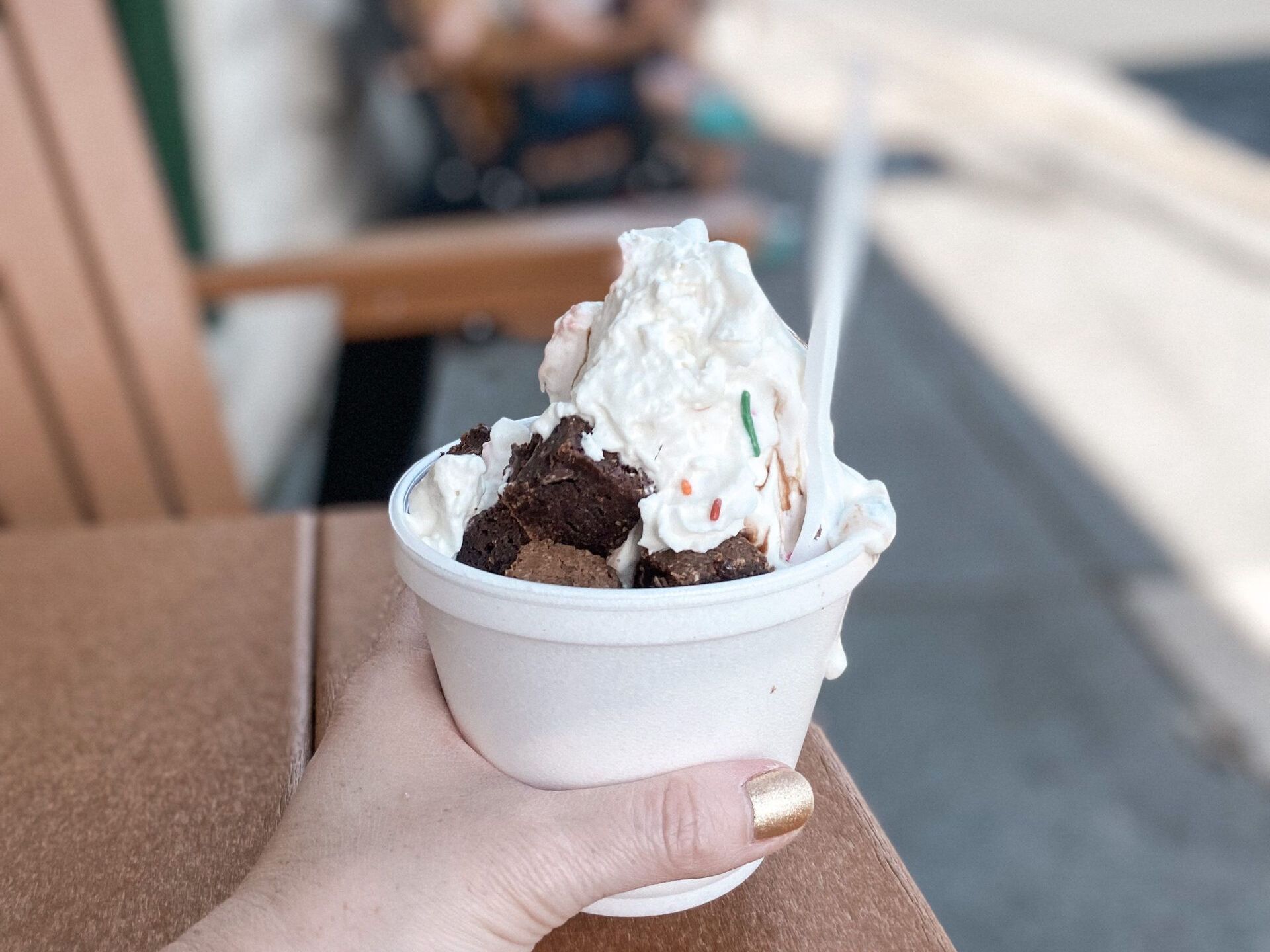 A person is holding a cup of ice cream with a spoon in it.