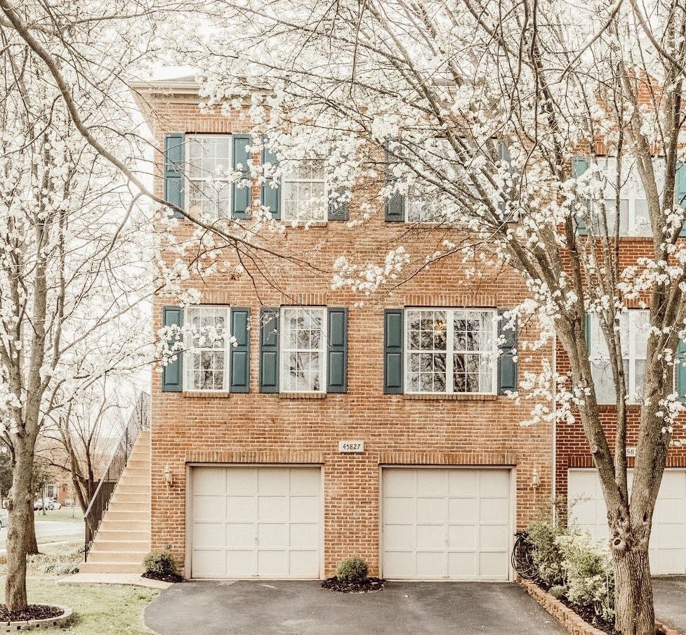A large brick house with two garages and trees in front of it. A large brick house with two garages and trees in front of it.
