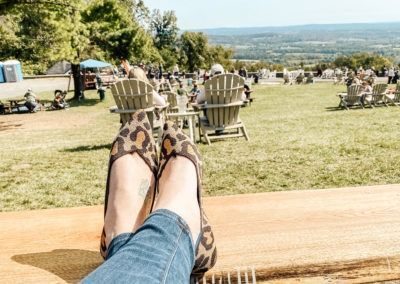 A person is sitting on a bench with their feet up in front of a field of chairs.