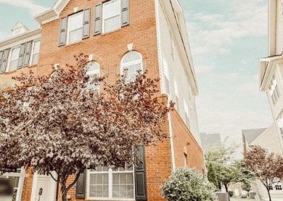 A brick house with a lot of windows and trees in front of it.