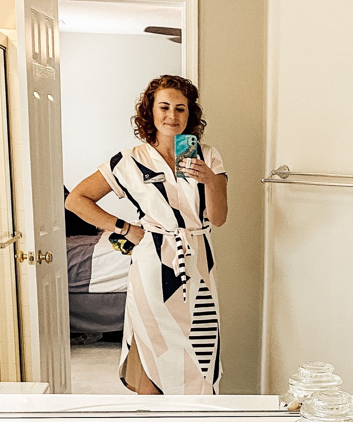 A woman in a dress is taking a selfie in front of a mirror.
