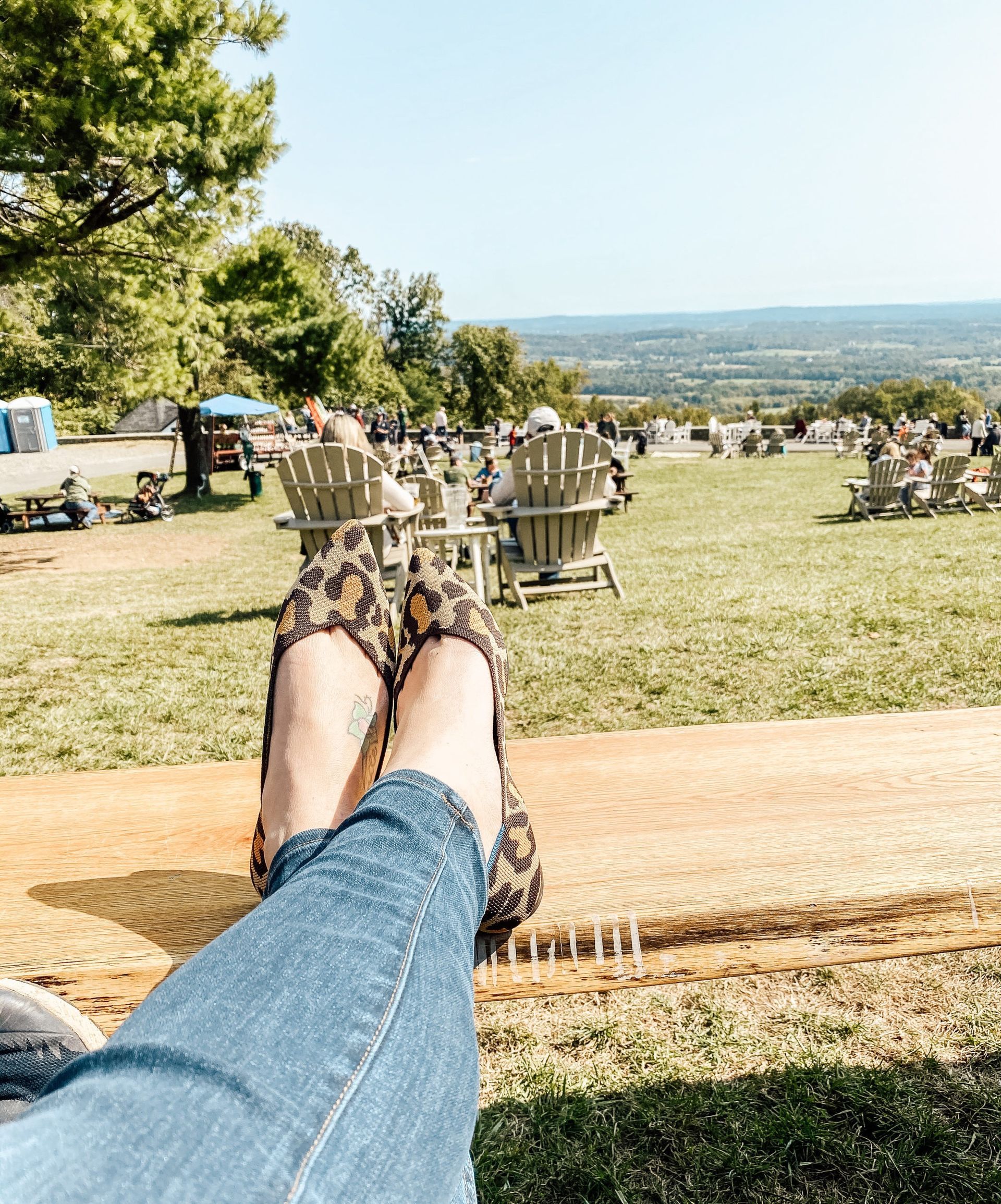 A person is laying on a bench with their feet up in front of a field of chairs.