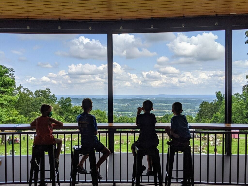 A group of children are sitting at a table looking out a window.