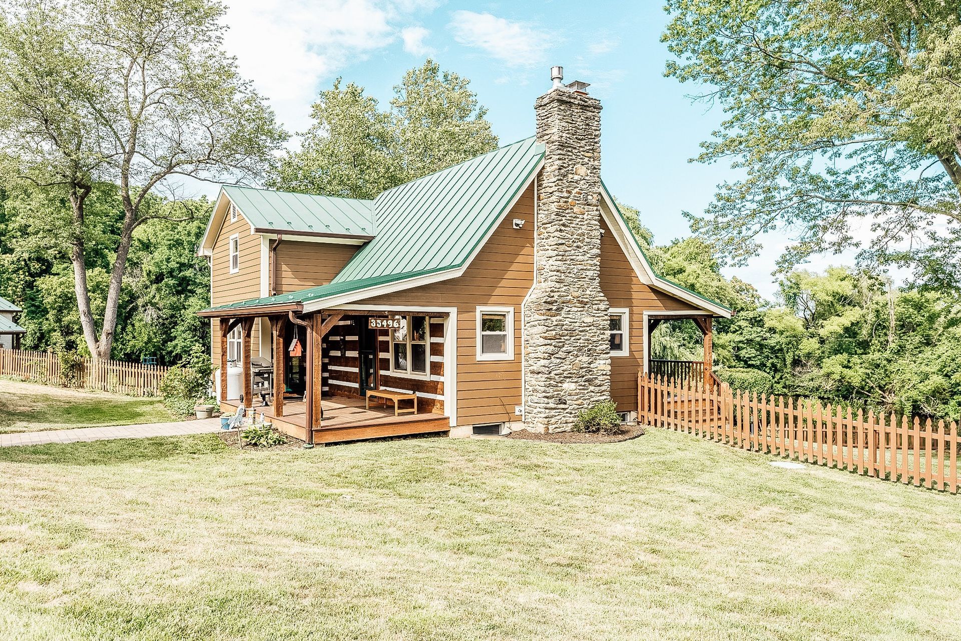 A small log cabin with a green roof and a stone chimney is sitting in the middle of a grassy field.