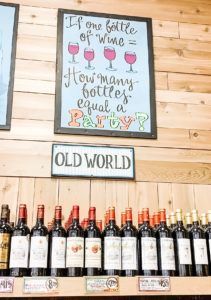 A sign on a wooden wall says `` if one bottle of wine = how many bottles equal a party ''.