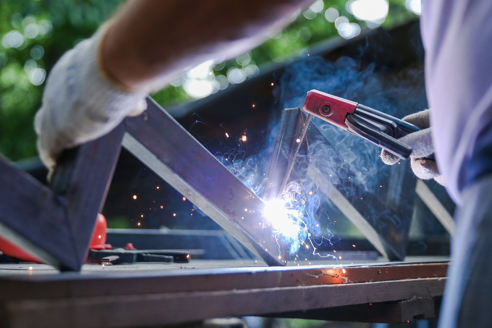 Welder working on metal frame, with bright sparks in an outdoor workshop