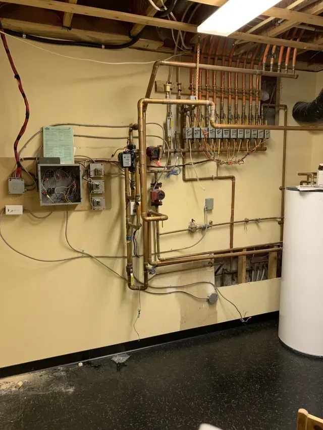 A room with a lot of pipes and wires on the wall