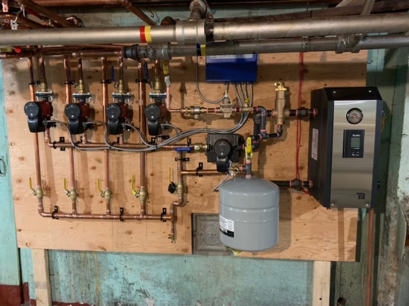 A wall with a lot of pipes and valves on it.