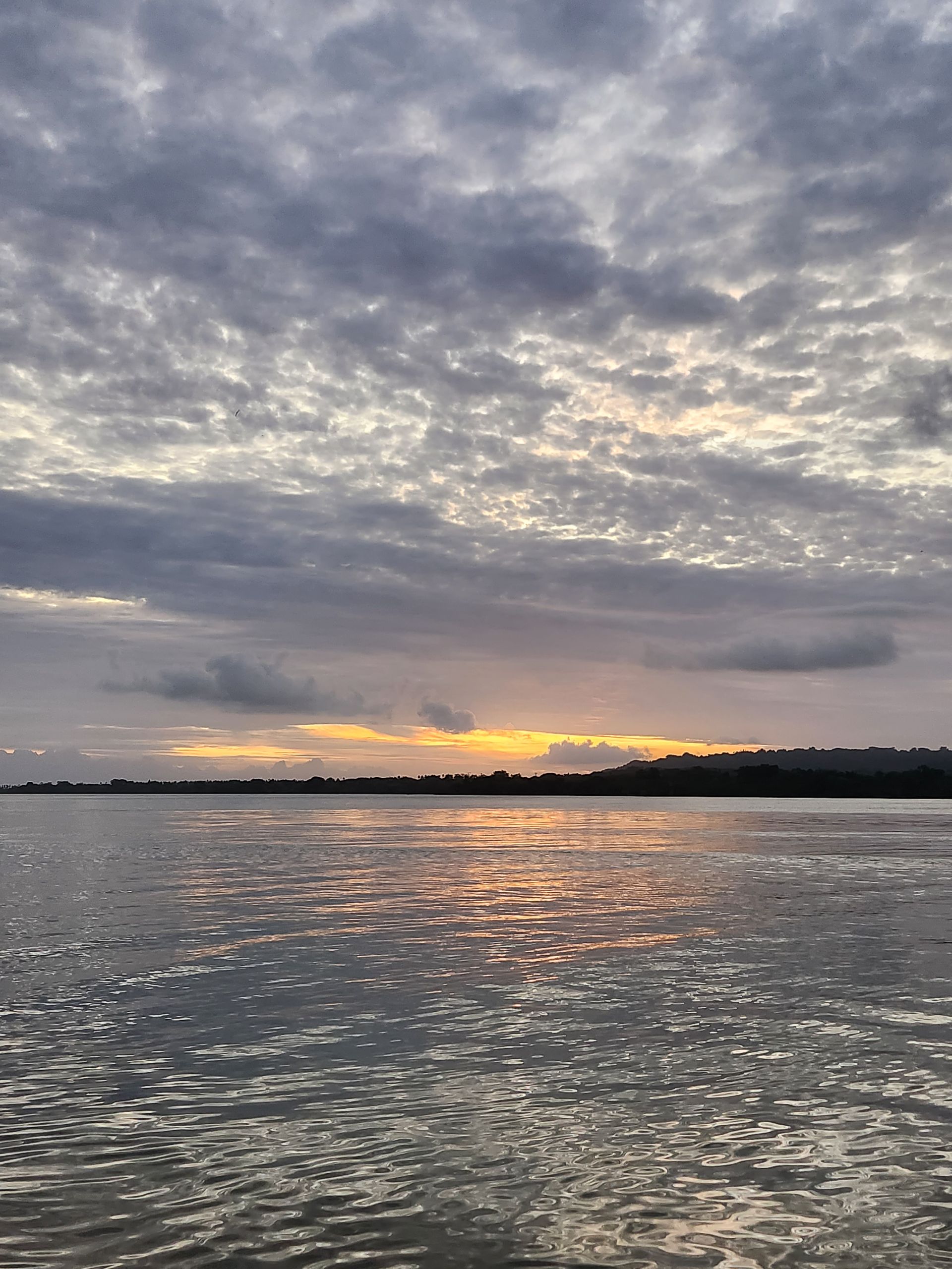 A sunset over a body of water with clouds in the sky