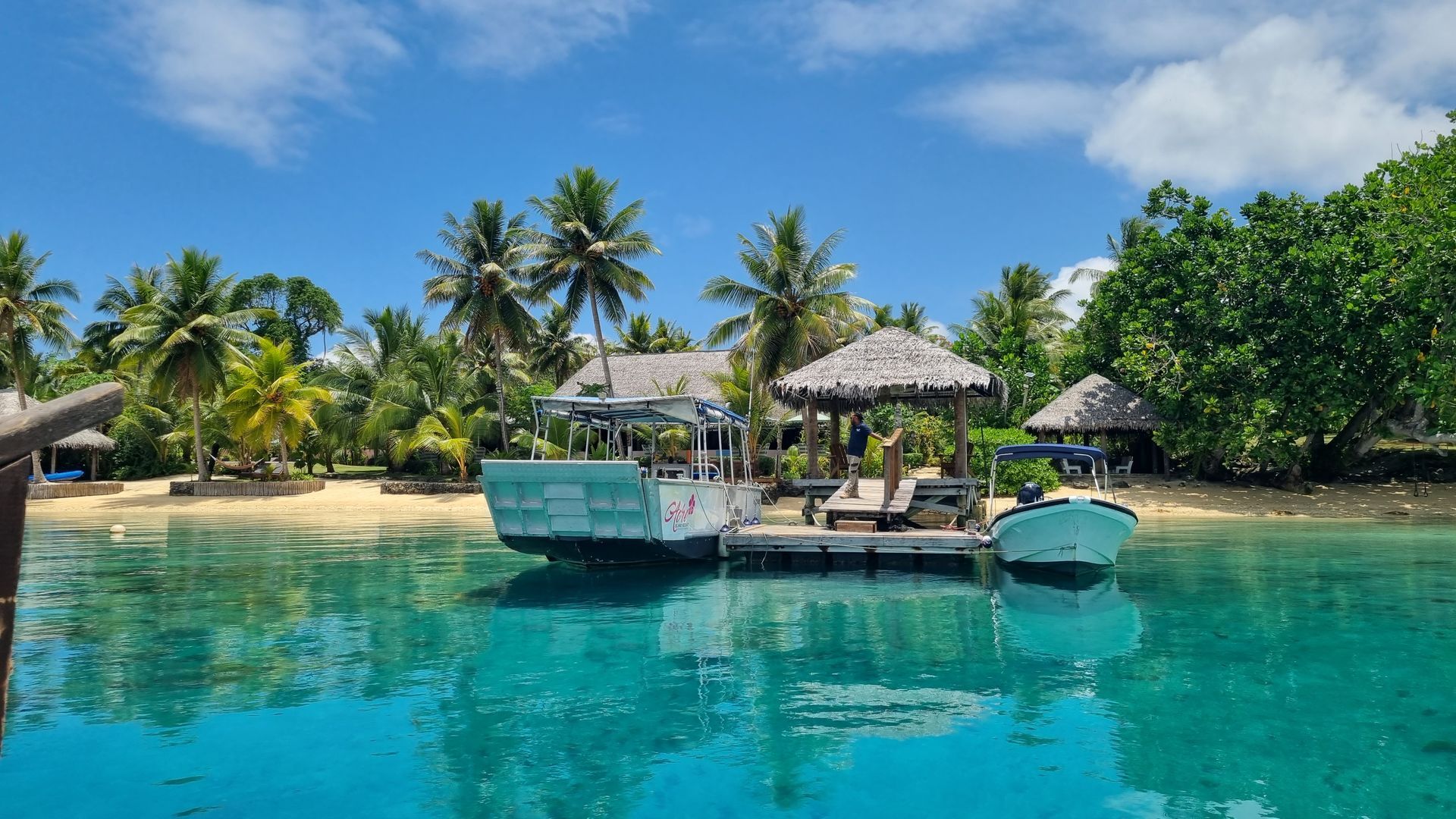 A boat is floating on top of a body of water next to a beach.