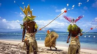 Two men are standing on a beach holding sticks.
