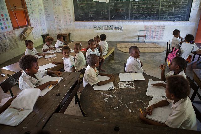 A group of children are sitting at tables in a classroom.