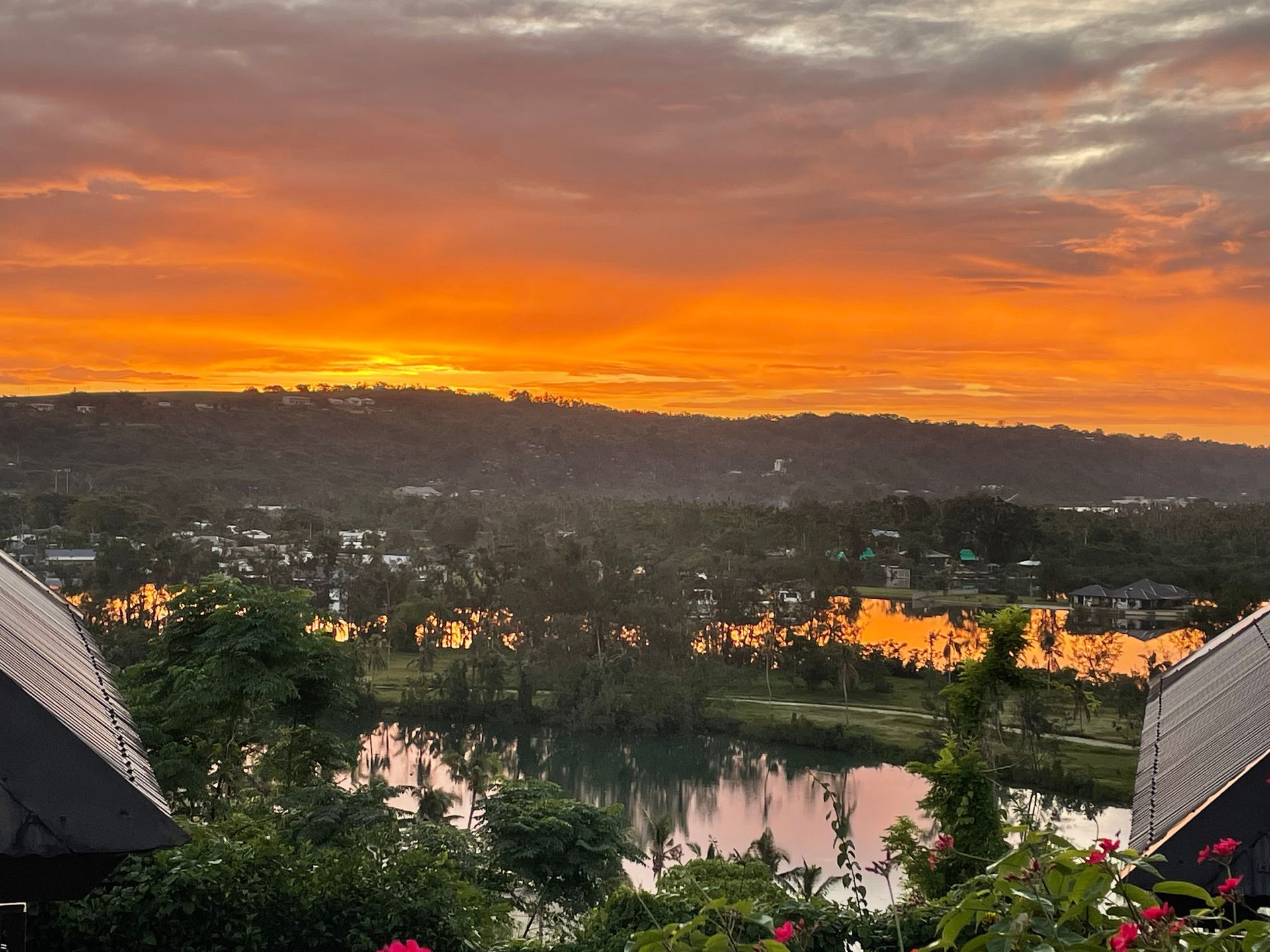 A sunset over a lake with a few houses in the foreground