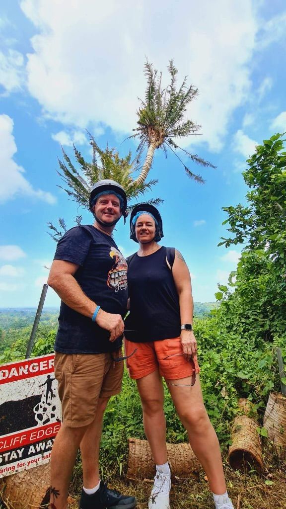 A man and a woman are standing next to each other in front of a sign.