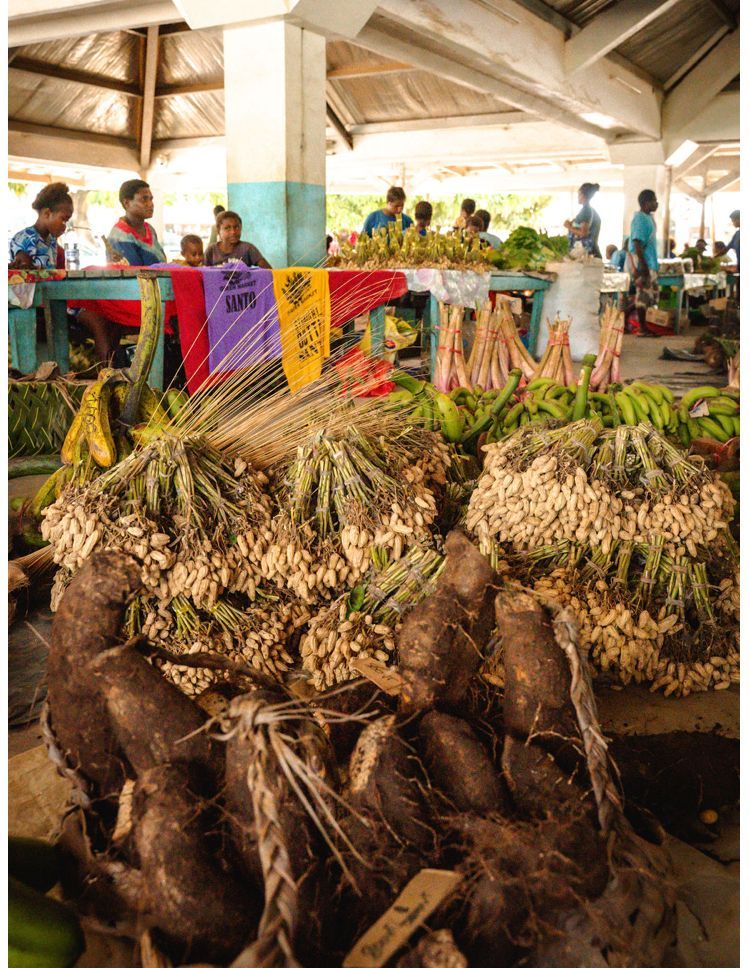 A bunch of vegetables are stacked on top of each other in a market.