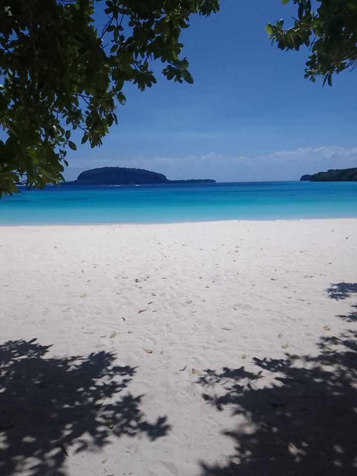 A white sandy beach with a blue ocean in the background