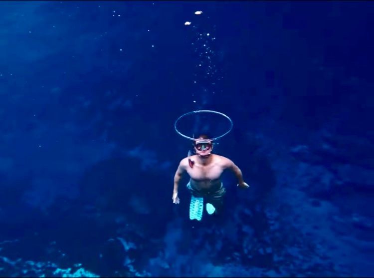 A man is swimming in the ocean with a hoop around his head