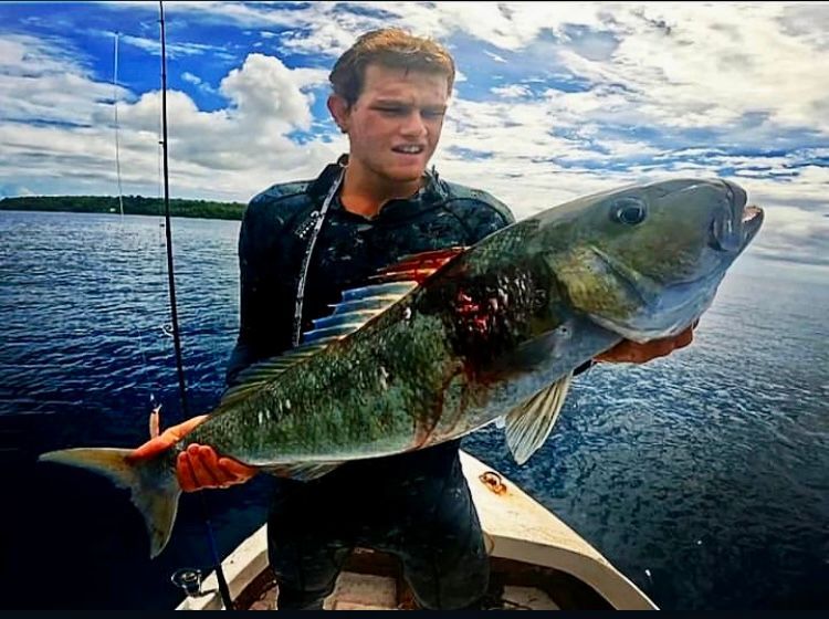 A man is holding a large fish on a boat