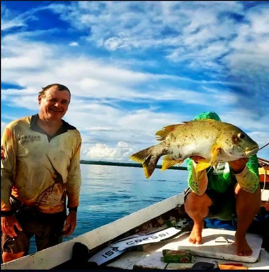 A man is holding a large fish on a boat