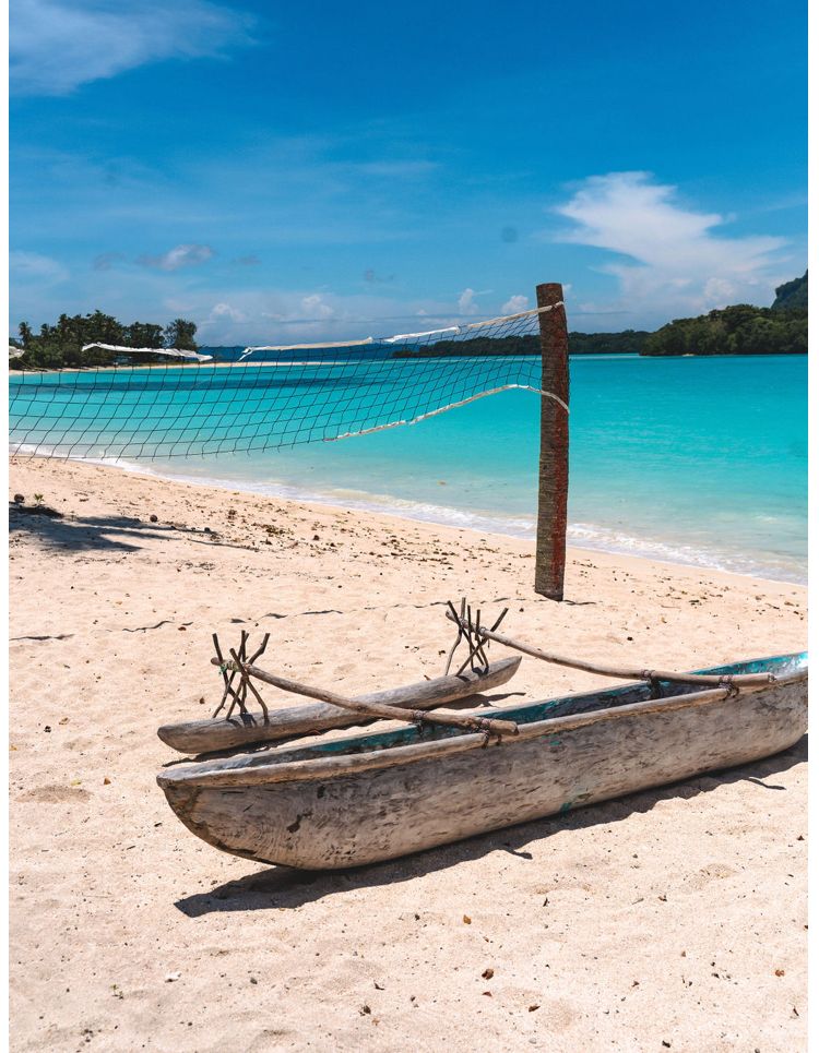 A boat is sitting on the beach next to a volleyball net.