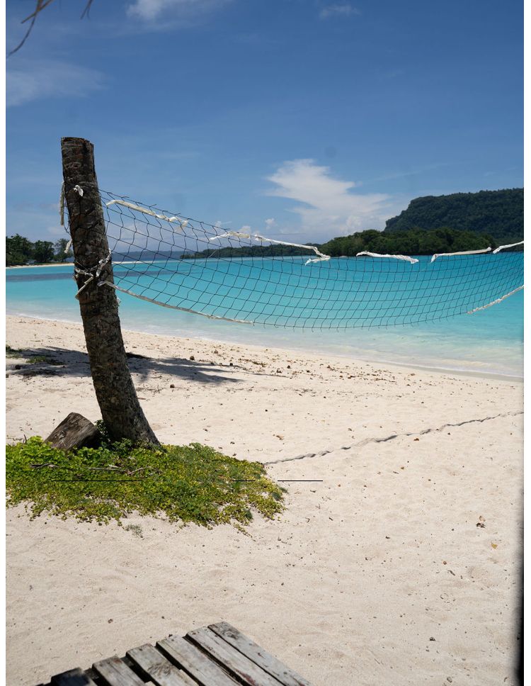A beach with a volleyball net in the sand