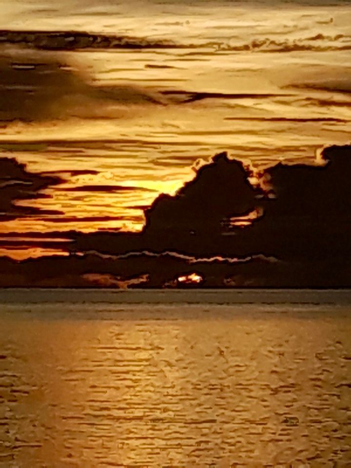 A sunset over a body of water with clouds in the sky