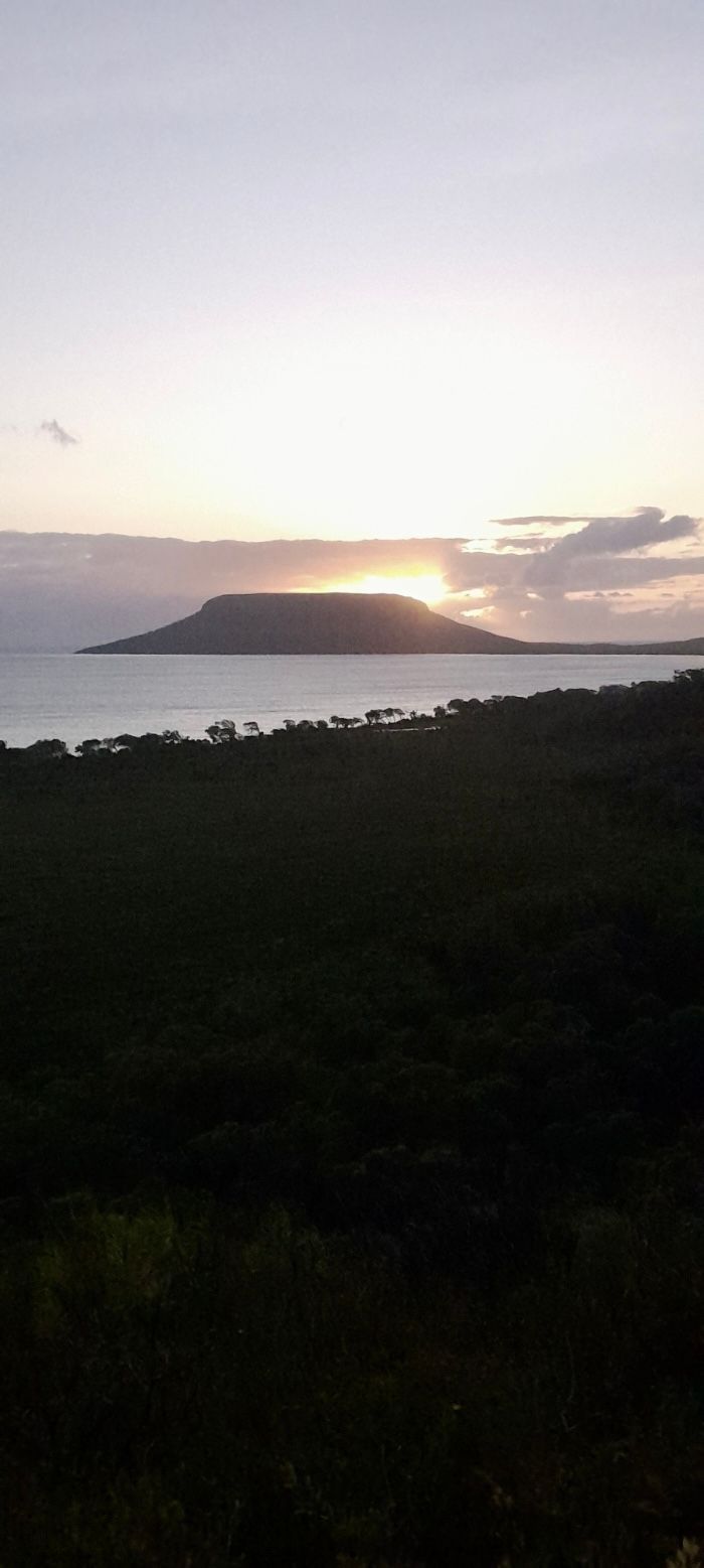 A sunset over a body of water with a small island in the distance