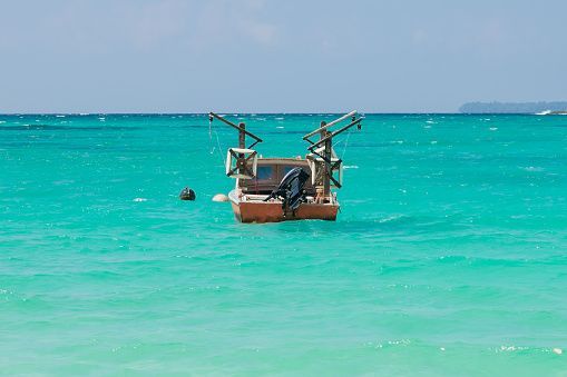 A small boat is floating on top of a turquoise ocean.