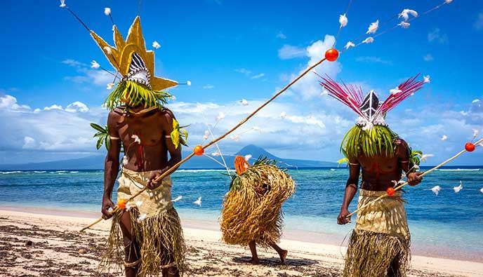 Two men are standing on a beach holding sticks.