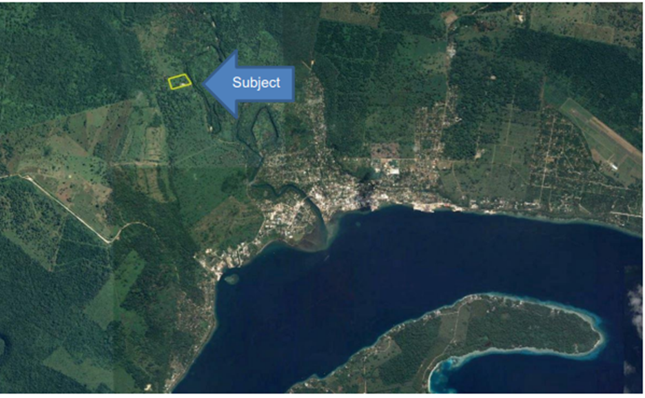Aerial view showing a coastal town, forested areas, and a body of water; the subject area is highlighted