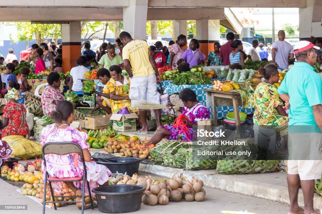 A crowd of people are buying fruits and vegetables at a market.