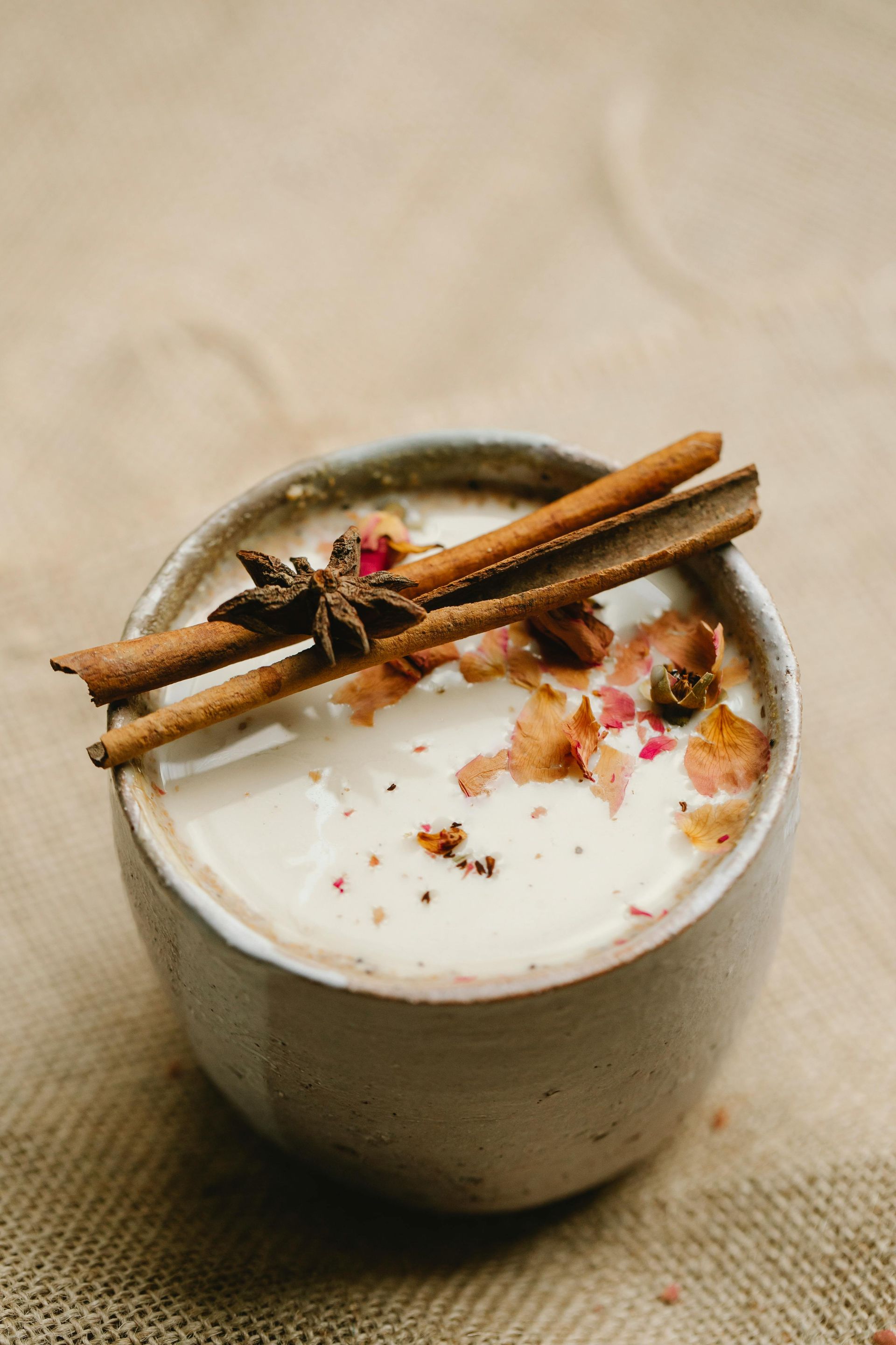A cup of Vanuatu Cacao & chai tea with cinnamon sticks and rose petals on top.